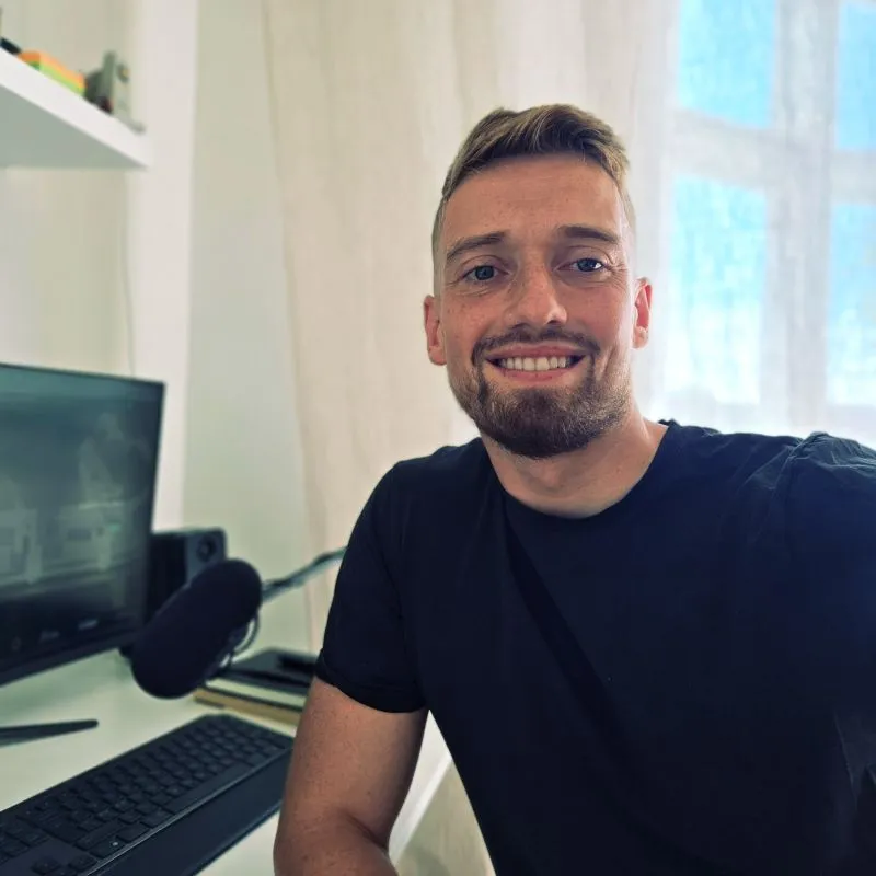 Michael Kirkegaard Clausen, smiling at his Copenhagen home office with a podcast microphone on the desk. Founder of Profit Studio and CEO of Maxis.dk and Billigtraening.dk. Profit Engineering consultant offering full-funnel marketing (SEO, Google Ads, Paid Social, retention, AI automation) for Shopify e-commerce brands.